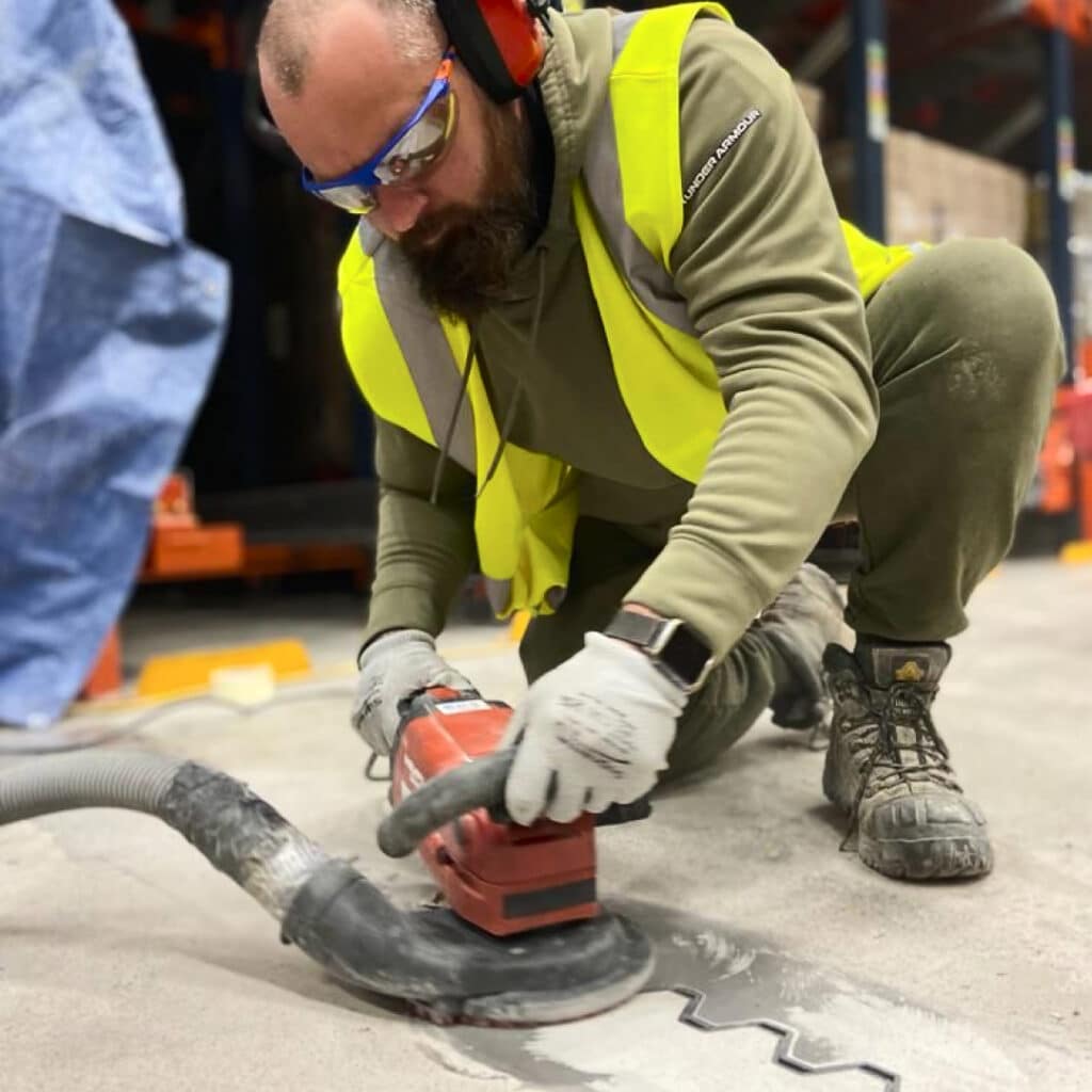 Lee from MKZ Construction blasting a section of repaired concrete floor in a warehouse