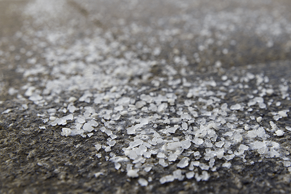 A close-up shot of de-icing salt on a concrete floor surface.