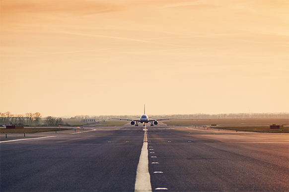 A photo of a plane landing on a pavement quality concrete runway at sunset